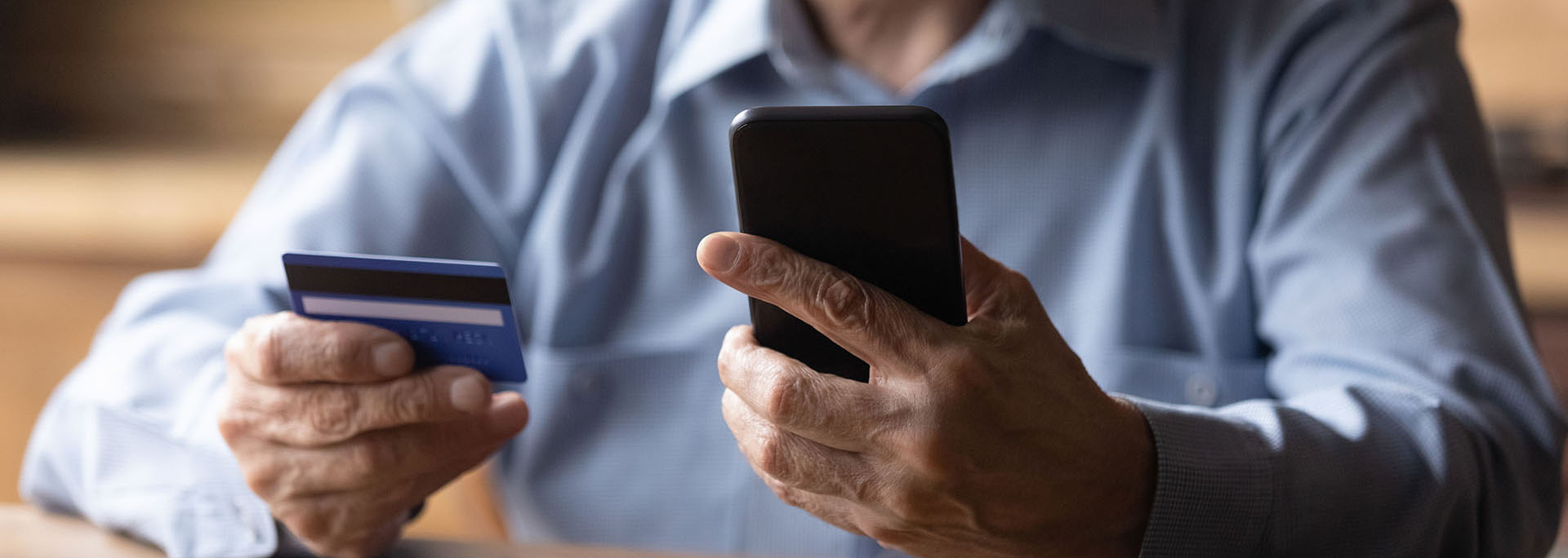 Close up mature man using phone, holding plastic credit card stock photo