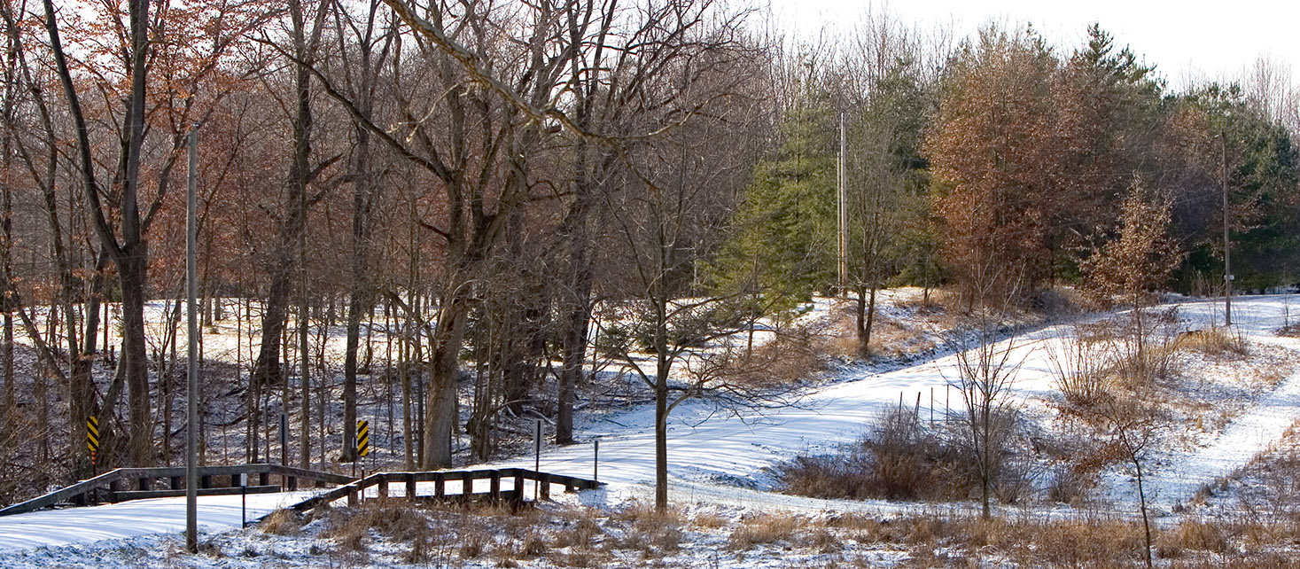 Country road with bridge in autumn, lightly snow covered.